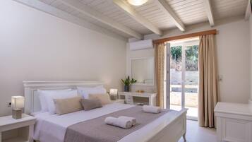A neatly arranged bedroom with a bed, bedside tables, a desk, and a large window with curtains.