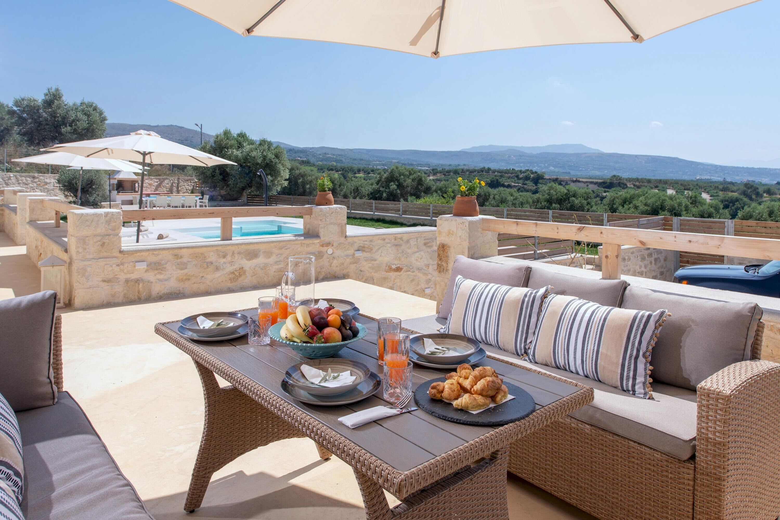 An outdoor dining area with a pool, wicker furniture, and a scenic view.