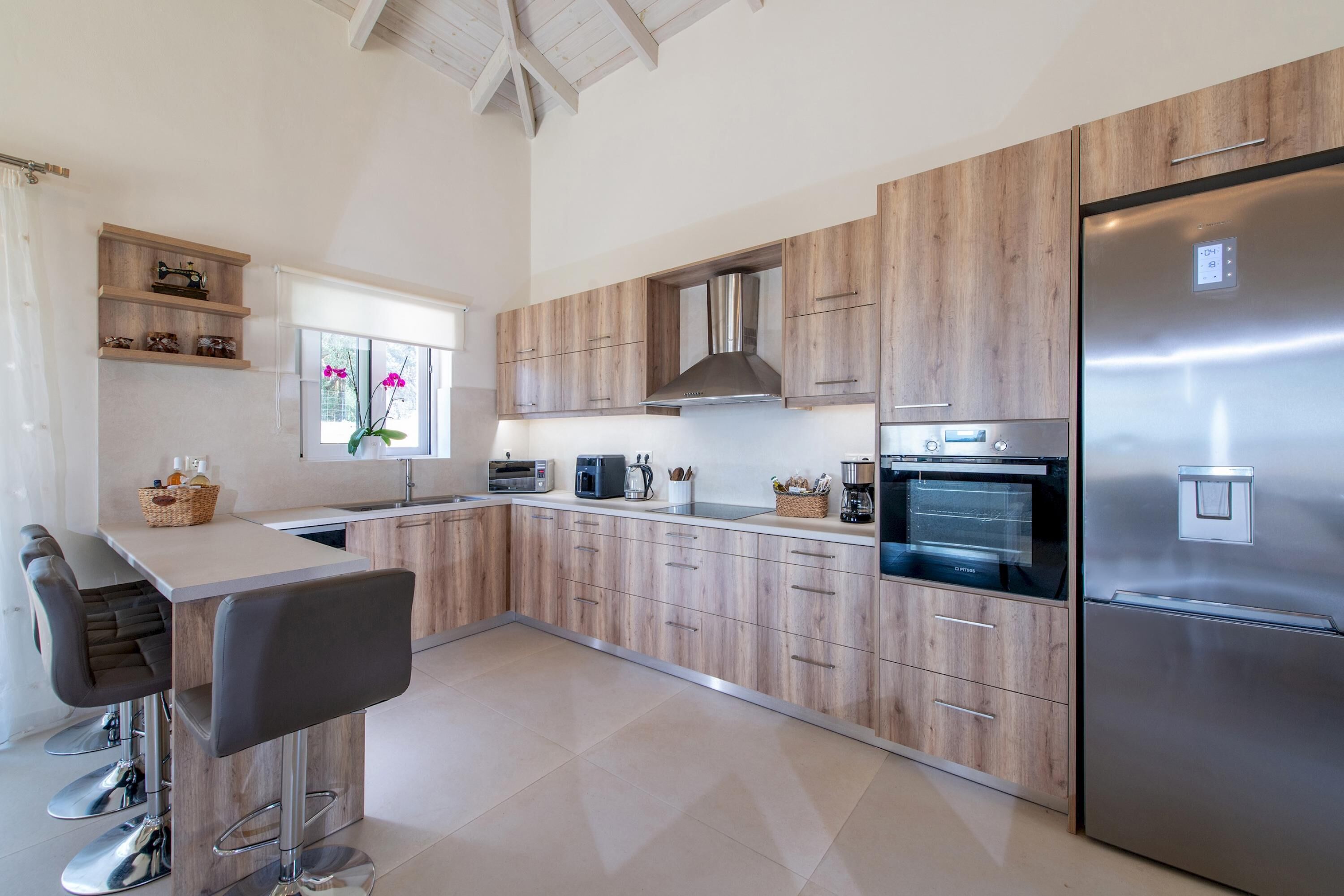 A modern kitchen with wooden cabinets, stainless steel appliances, and a bar area with stools.