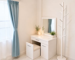 A bathroom with a white vanity, a mirror, a plant, and a towel rack.