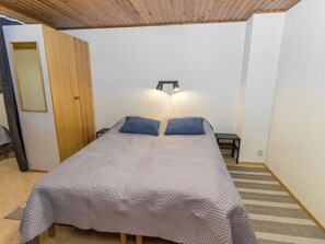Une chambre à coucher avec un lit, deux oreillers, une table de chevet, une lampe et une porte en bois.