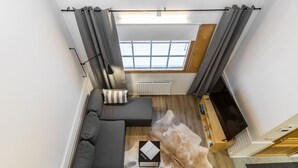 Un salon moderne avec un canapé d’angle, un tapis en cuir et un téléviseur à écran plat.