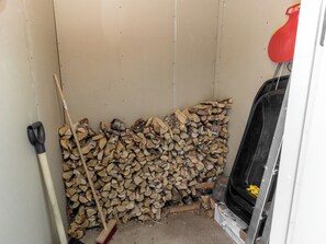 Un área de almacenamiento con un montón de leña, una escoba y una pala.