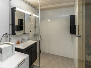 Ein modernes Badezimmer mit einer Duschkabine aus Glas, einem weißen Waschbecken und einem Spiegel mit schwarzem Rahmen.