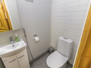 Une petite salle de bain propre, avec un lavabo blanc, des toilettes et un sèche-mains.