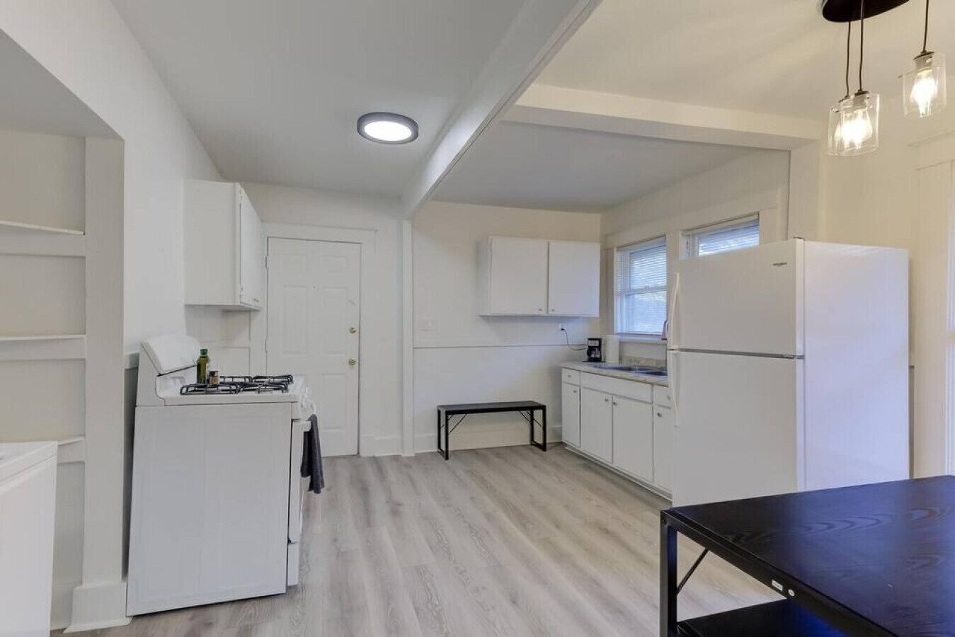 Una cocina compacta con armarios blancos, una estufa y un refrigerador.