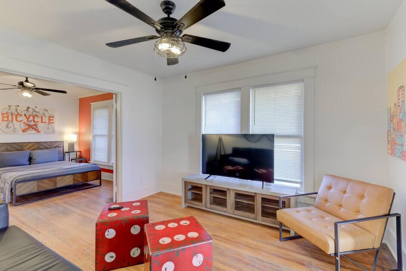 A modern living room with a bed, a TV, and a ceiling fan.