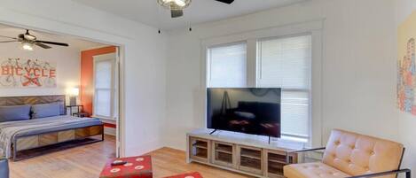 A modern living room with a bed, a TV, and a ceiling fan.