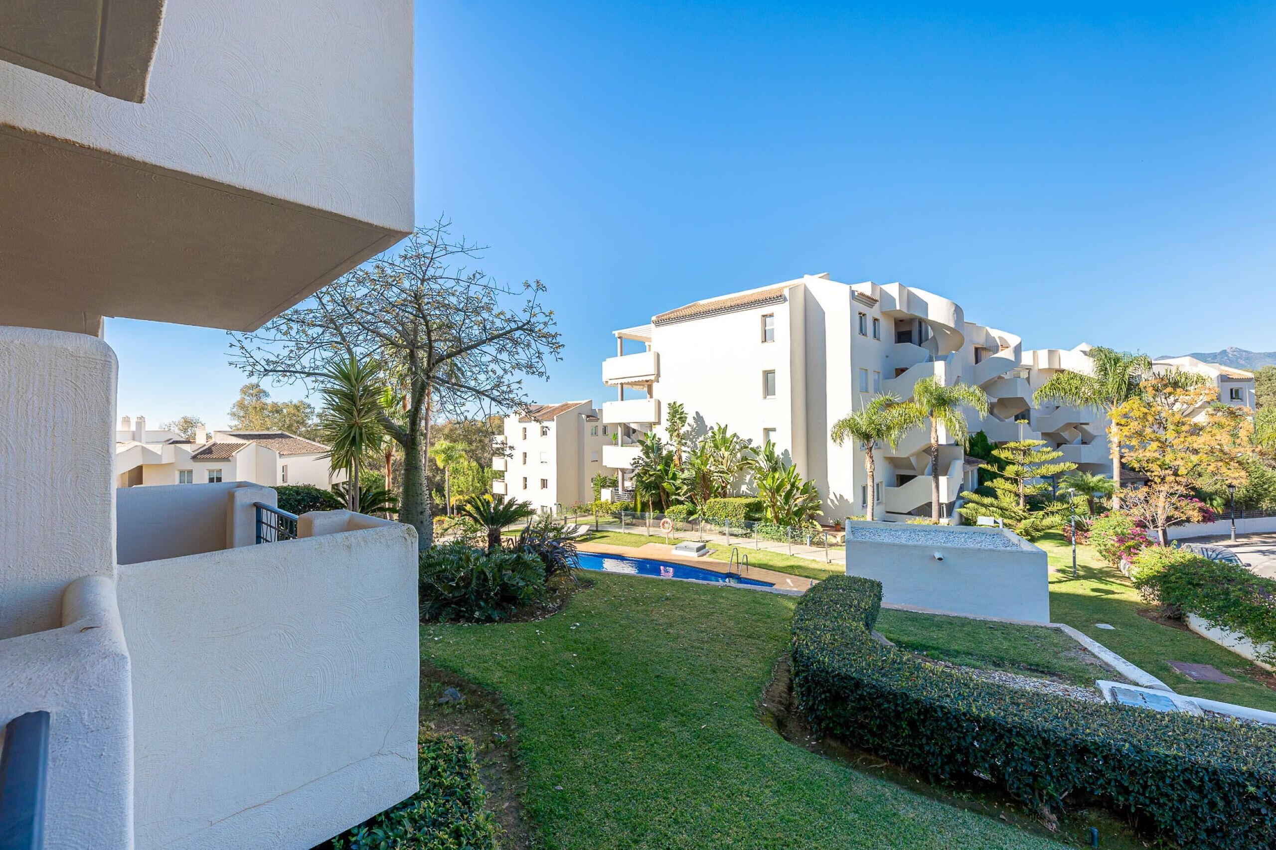 Un edificio residenziale moderno con numerosi balconi, una piscina e giardini curati.