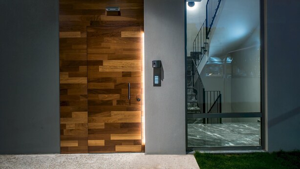 A modern entrance with a wooden panel door and a glass door leading to a staircase. - Athinais Apartments (Heraklion)