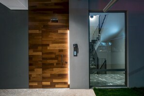 A modern entrance with a wooden panel door and a glass door leading to a staircase. - Athinais Apartments (Heraklion)