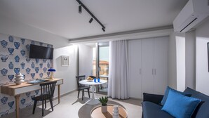 A modern living room with a black sofa, a round coffee table, and a dining area with a white table and chairs. - Athinais Apartments (Heraklion)