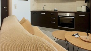 A modern kitchen with dark cabinets, a stainless steel oven, and a hanging light fixture. - Casa Kali 3 Apartment (Heraklion)