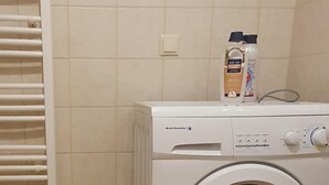 A front-loading washing machine with a control panel, a bottle of liquid soap, and a bottle of fabric softener on top. - Casa Kali 3 Apartment (Heraklion)