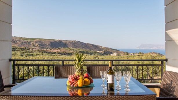 A table with a fruit platter and wine glasses on a balcony overlooking a scenic landscape. - Villa Chrissi Kissamos (Kissamos)