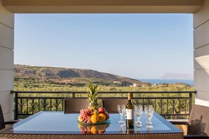 Une table avec un assortiment de fruits et des verres à vin, placée sur un balcon donnant sur un paysage magnifique.