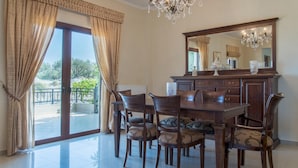 A dining area with a large wooden table, four chairs, a chandelier, and a large mirror above the table. - Villa Chrissi Kissamos (Kissamos)