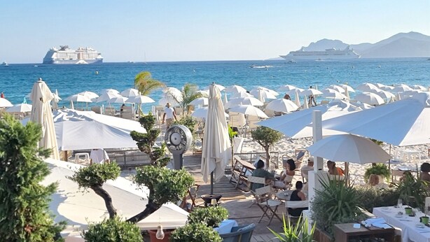 A beachside restaurant with outdoor seating, umbrellas, and a view of the sea and cruise ships. - Villa Les Margoutons – Family-friendly villa with heated private pool, sea view and large garden near Cannes (Tanneron)