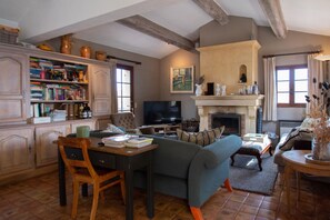 A cozy living room with a fireplace, a television, a bookshelf, and a comfortable seating area.