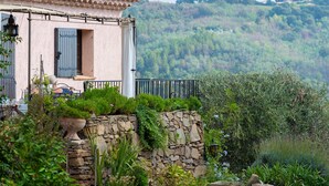 A rustic house with a stone wall, a balcony, and a lush garden. - Villa Les Margoutons – Family-friendly villa with heated private pool, sea view and large garden near Cannes (Tanneron)