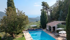 A rectangular swimming pool with a tiled deck, surrounded by a grassy area and trees. - Villa Les Margoutons – Family-friendly villa with heated private pool, sea view and large garden near Cannes (Tanneron)