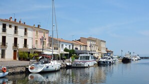 Un port de plaisance avec des bateaux amarrés le long de la rive, des bâtiments dotés de balcons et un ciel dégagé.
