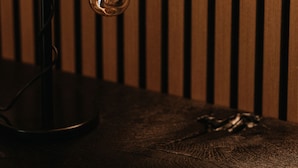 A modern lamp with a wooden base and a glass bulb, positioned against a wooden slat wall.