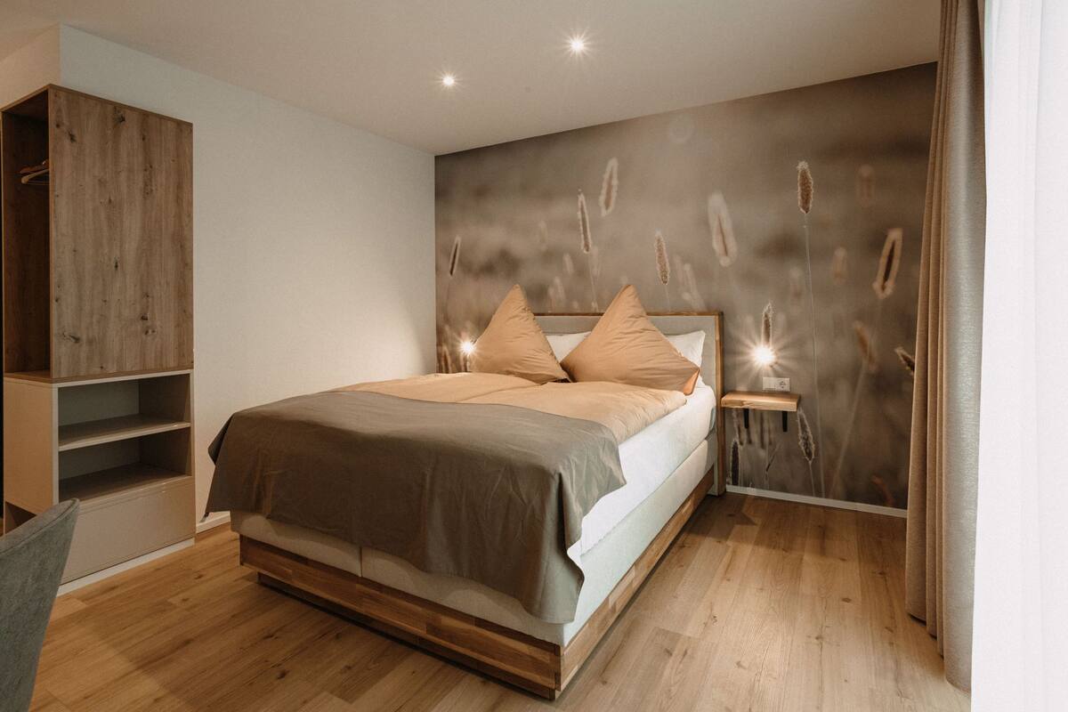 A modern bedroom with a wooden bed, a built-in wardrobe, and a wall-mounted shelf.