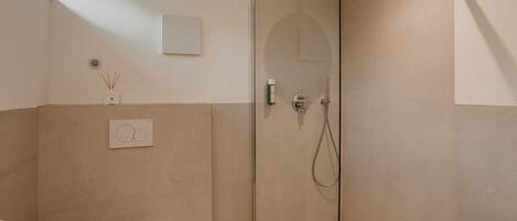 Un baño moderno con cabina de ducha de vidrio, inodoro y difusor de pared.