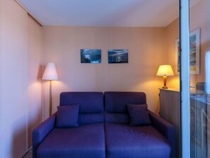 Una habitación con sofá cama doble, dos lámparas de pared y dos cuadros enmarcados.