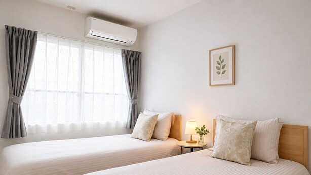 Ein Hotelzimmer mit zwei Betten, einer Klimaanlage, einer Lampe und einem gerahmten Bild an der Wand.