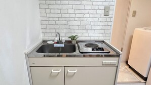 Eine kleine Küche mit Spüle, einer Zimmerpflanze und einer Mikrowelle.