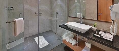 A modern bathroom with a glass-enclosed shower, a sink with a black countertop, and a mirror above the sink.