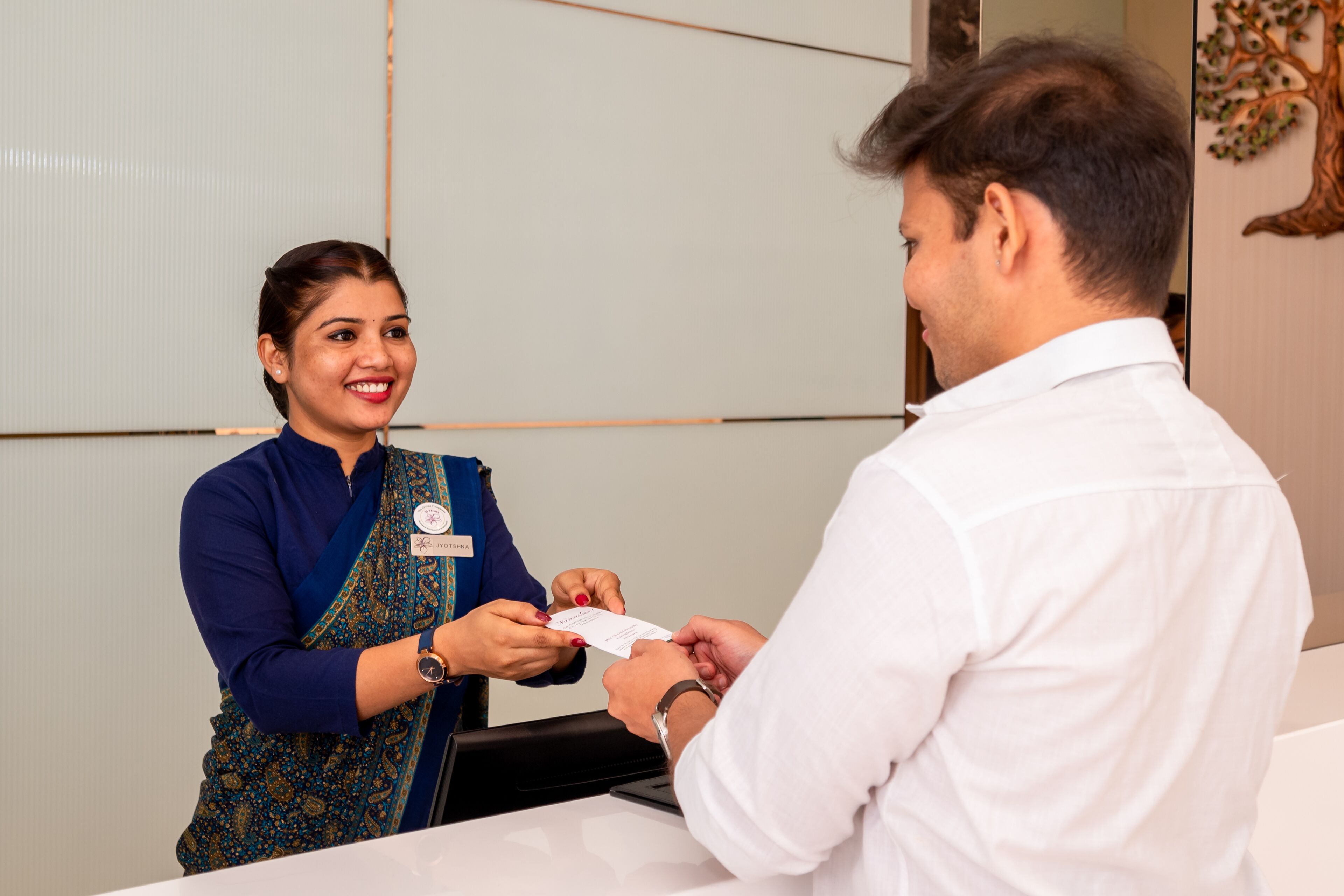 A reception area with a reception desk, a name tag, and a person handing over a document.