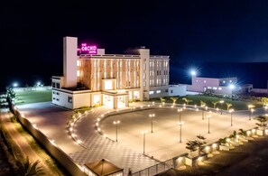 Un hotel moderno con un patio central iluminado por faroles y un llamativo letrero de neón.