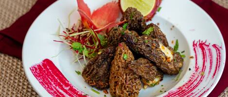 A plate of food with a red and white design, garnished with herbs and a slice of lime.
