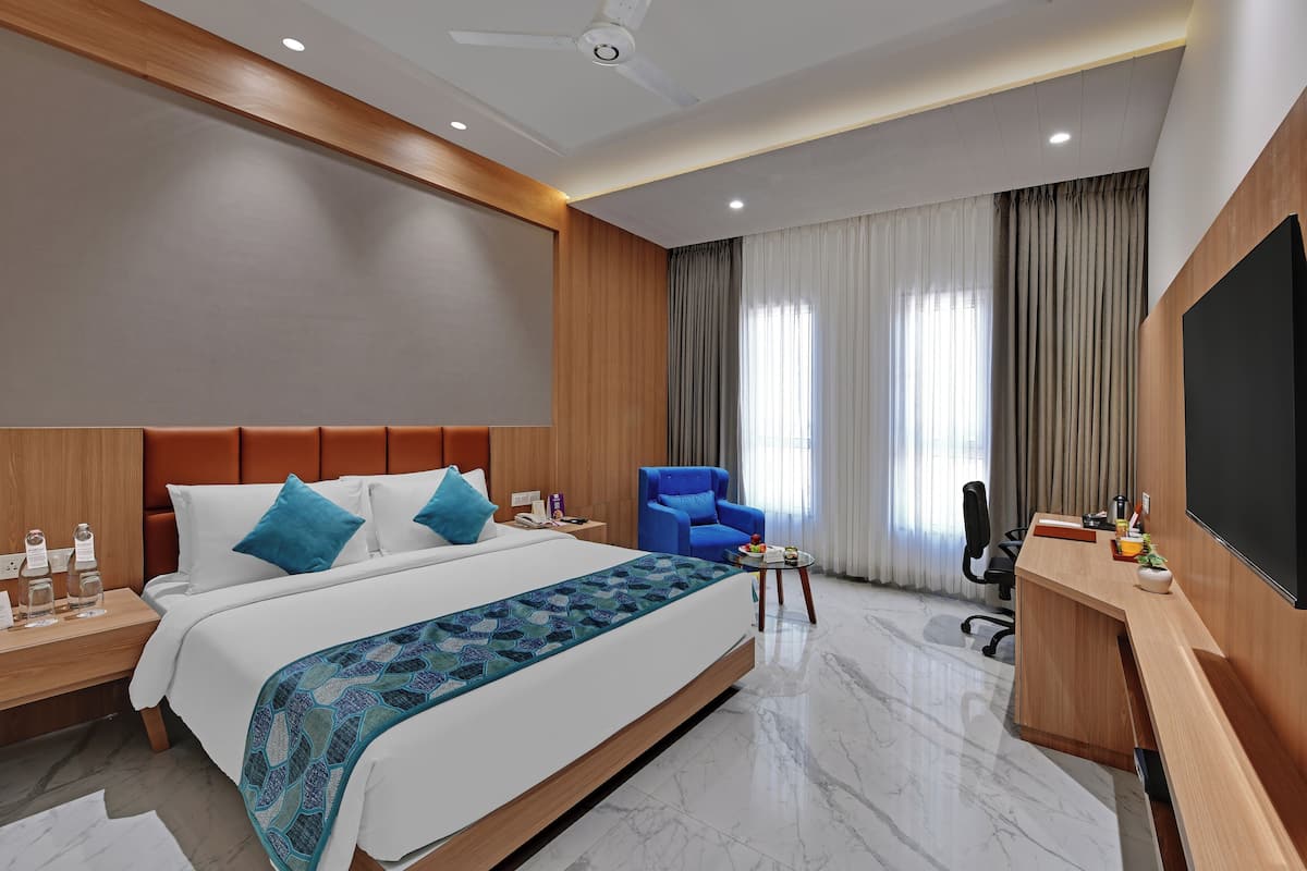 Quarto de hotel moderno com uma cama grande, uma mesa, uma cadeira e uma televisão.