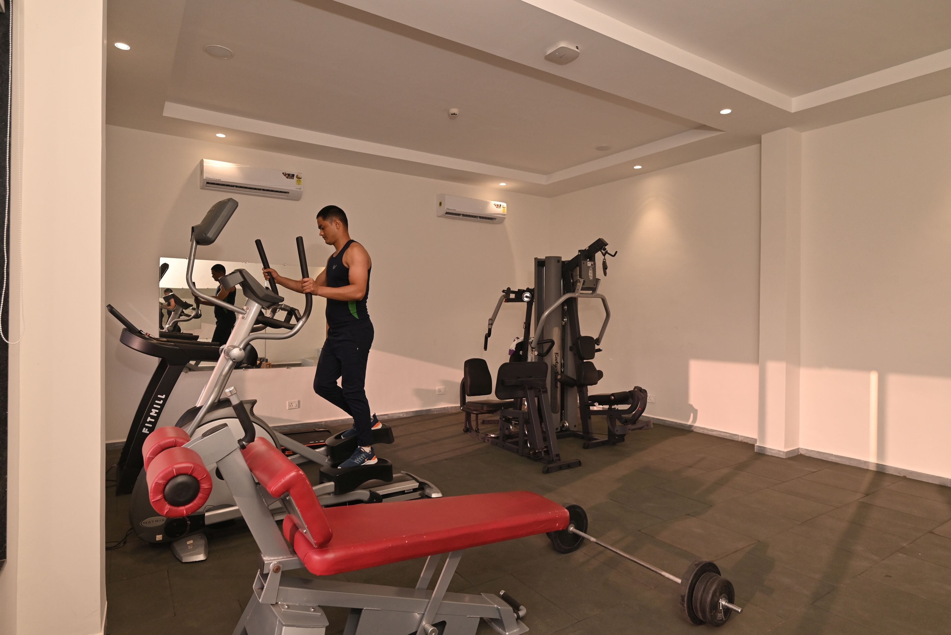 A gym with a treadmill, weight bench, and various exercise machines.