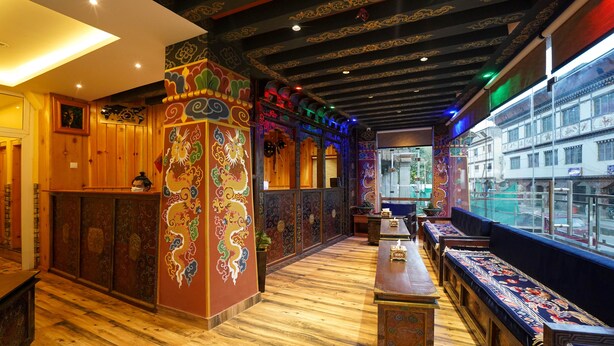 A traditional interior with wooden floors, a central seating area, and decorative wall panels. - Hotel Gakyidiana (Paro)