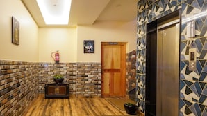 A hallway with wooden flooring, a brick accent wall, a 'Staff Only' door, an elevator, and a fire extinguisher. - Hotel Gakyidiana (Paro)