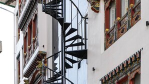 A multi-story building with ornate balconies and a central spiral staircase. - Hotel Gakyidiana (Paro)