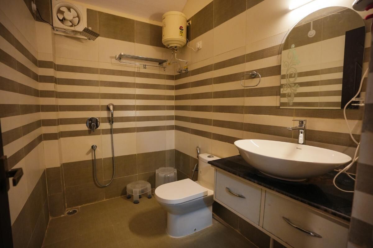 A bathroom with striped tiles, a white sink, a toilet, a shower, and a towel rack.