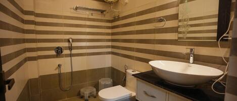A bathroom with striped tiles, a white sink, a toilet, a shower, and a towel rack.