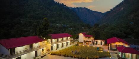 A hotel with multiple buildings, each with a red roof, situated in a valley surrounded by mountains.