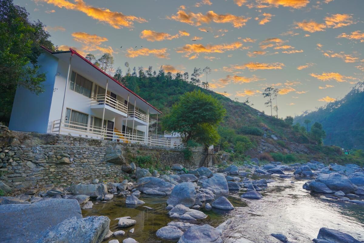 A modern building with a balcony overlooking a rocky riverbed.