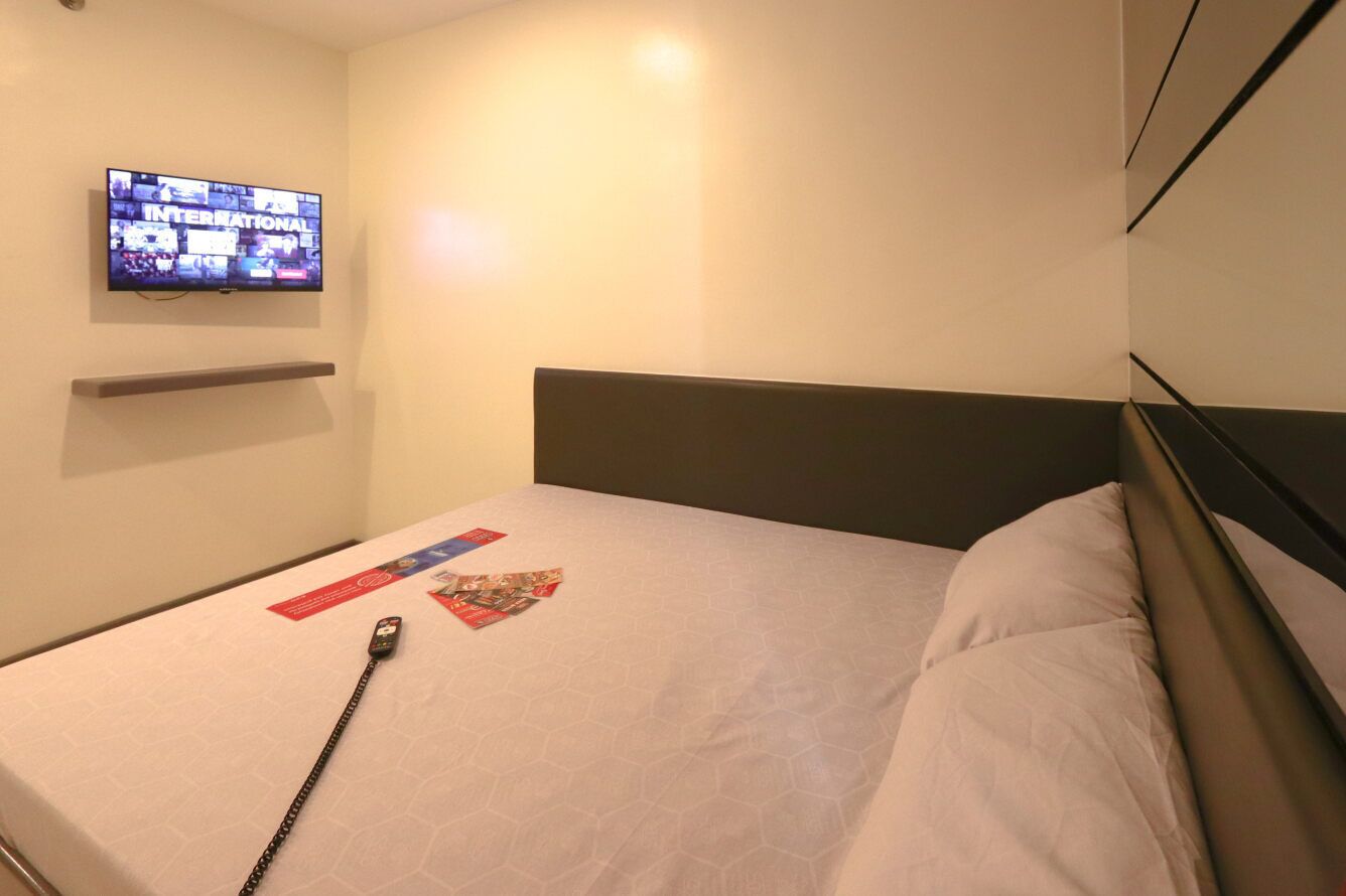 Habitación de hotel con cama, televisión de pantalla plana en la pared y mesita de noche.
