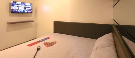 Habitación de hotel con cama, televisión de pantalla plana en la pared y mesita de noche.