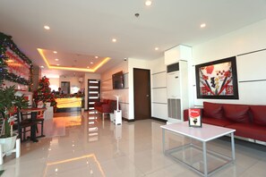 Una hall d'hotel moderna con un albero di Natale, una reception, un divano rosso e un'opera d'arte appesa al muro.