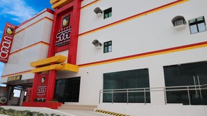 A modern hotel with a prominent red and yellow facade, a drive-in entrance, and large windows. - Hotel Sogo General Trias (General Trias)