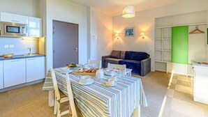 Un espacio habitable compacto con kitchenette, comedor y zona de estar.